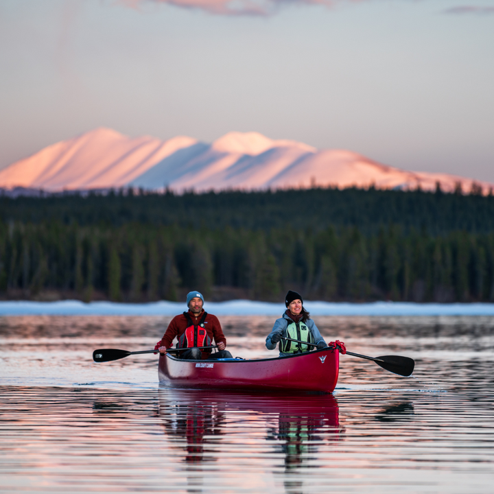 Black Pearl ST being paddle by a male and female (stern and bow respectfully) with beautiful snow-covered mountains 